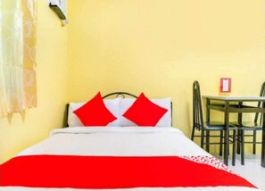 Ein Bett mit weißer und roter Bettdecke, zwei rote Kissen und ein schwarzes Kopfteil.