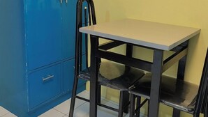 Una stanza con un armadietto blu, un tavolo e due sedie.