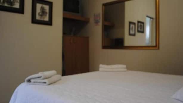 Una habitación de hotel con una cama, un armario y un espejo en la pared.
