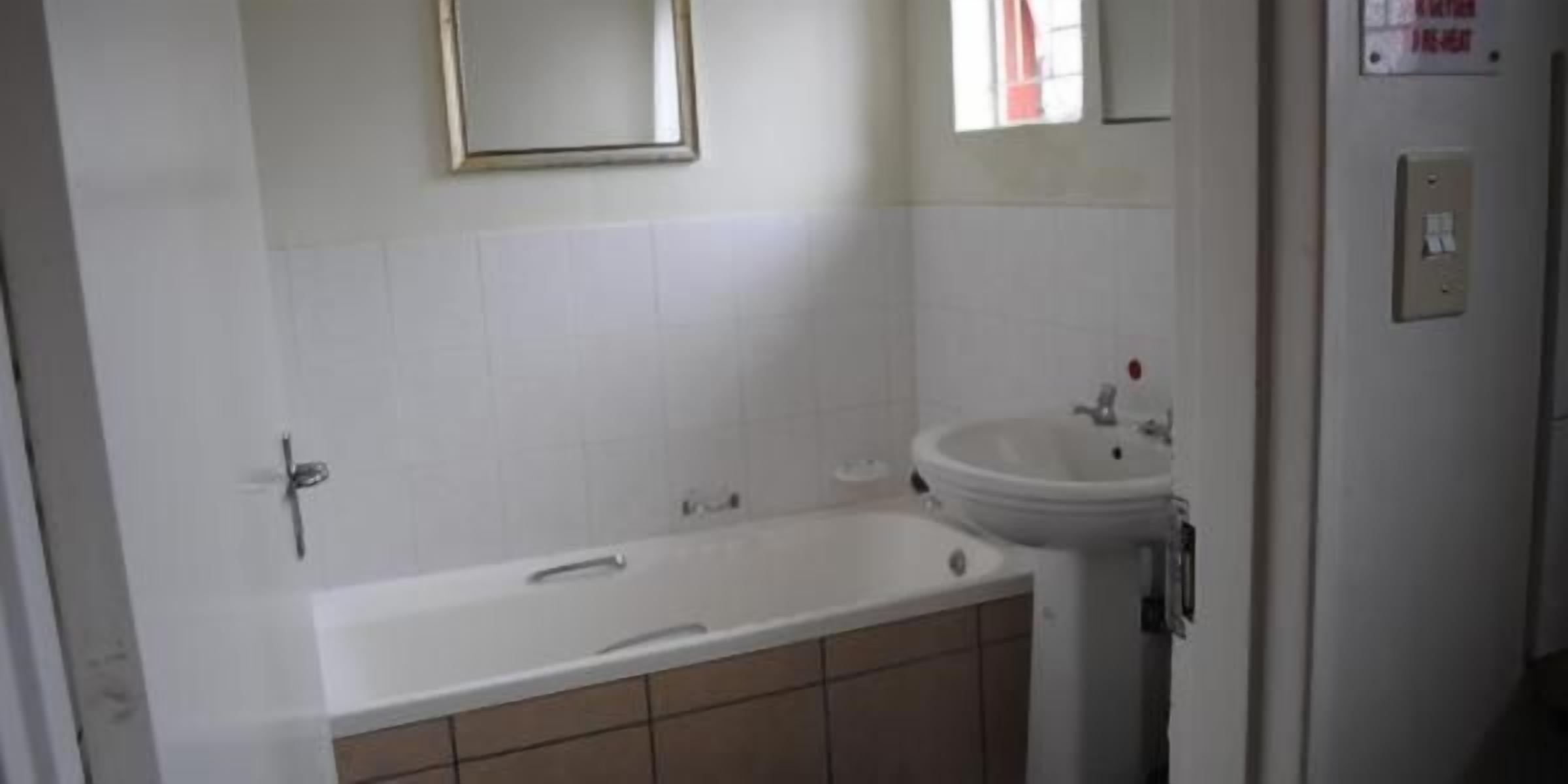 A bathroom with a bathtub, sink, and mirror.