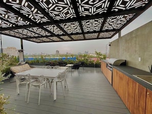 An outdoor patio with a dining area, a grill, and a view of the cityscape. - Be Mate Condesa Hipodromo (Mexico City)