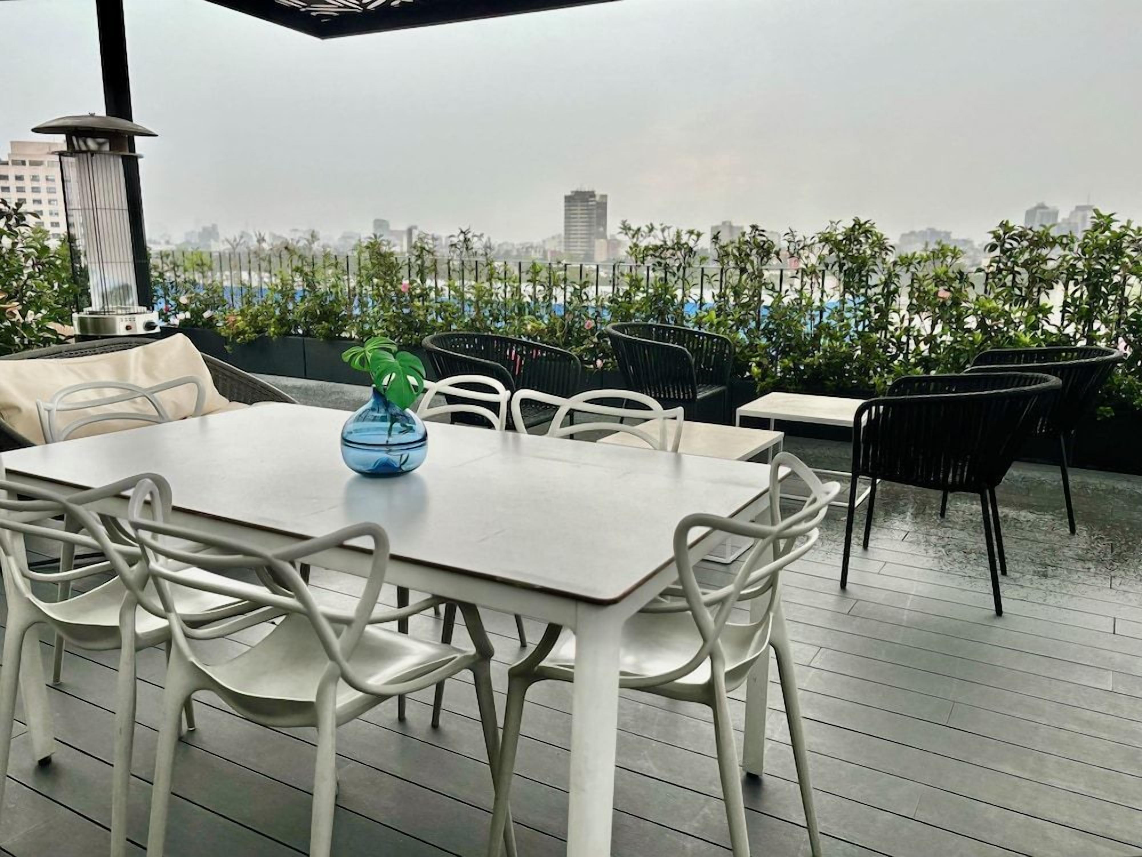 An outdoor seating area with a table and chairs, a decorative bowl, and a view of the cityscape.