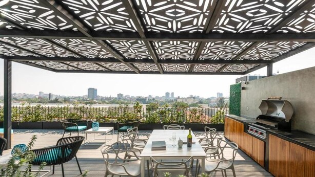 An outdoor patio with a view of a city skyline, featuring a grill and seating area. - Be Mate Condesa Hipodromo (Mexico City)