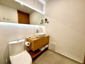 A modern bathroom with a toilet, a sink with a vessel basin, a mirror, and a wooden vanity. - Be Mate Condesa Hipodromo (Mexico City)
