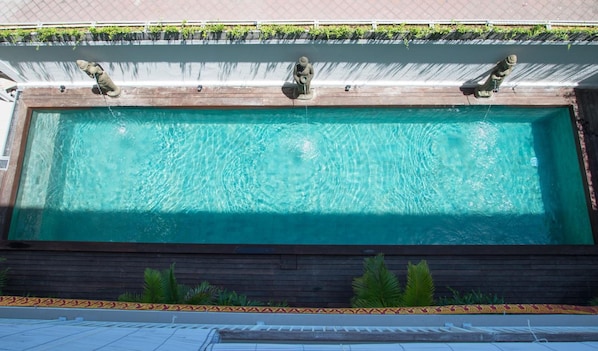 En rektangulär swimmingpool med ett trädäck och en låg mur.