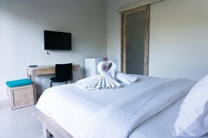 Ett hotellrum med en säng, ett skrivbord, en stol, en tv och en garderob.