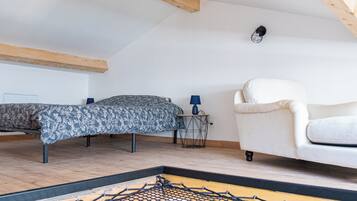 Una habitación con cama, una silla y una mesita de noche con lámpara.