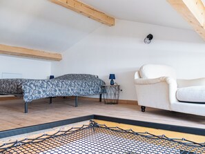 Ett rum med en säng, en stol och ett litet bord med en lampa.