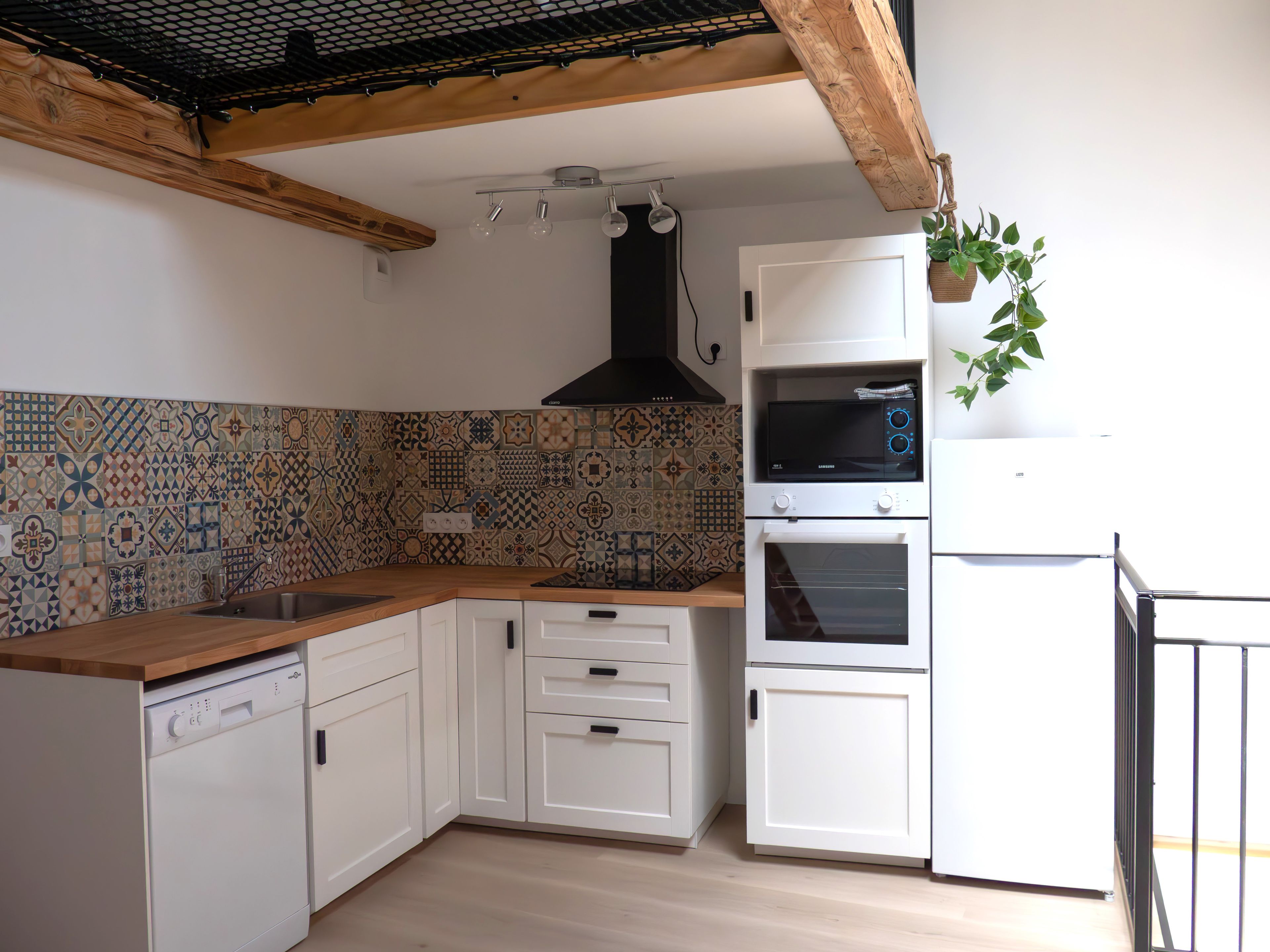 Una cocina con armarios blancos, lavavajillas, microondas y horno.