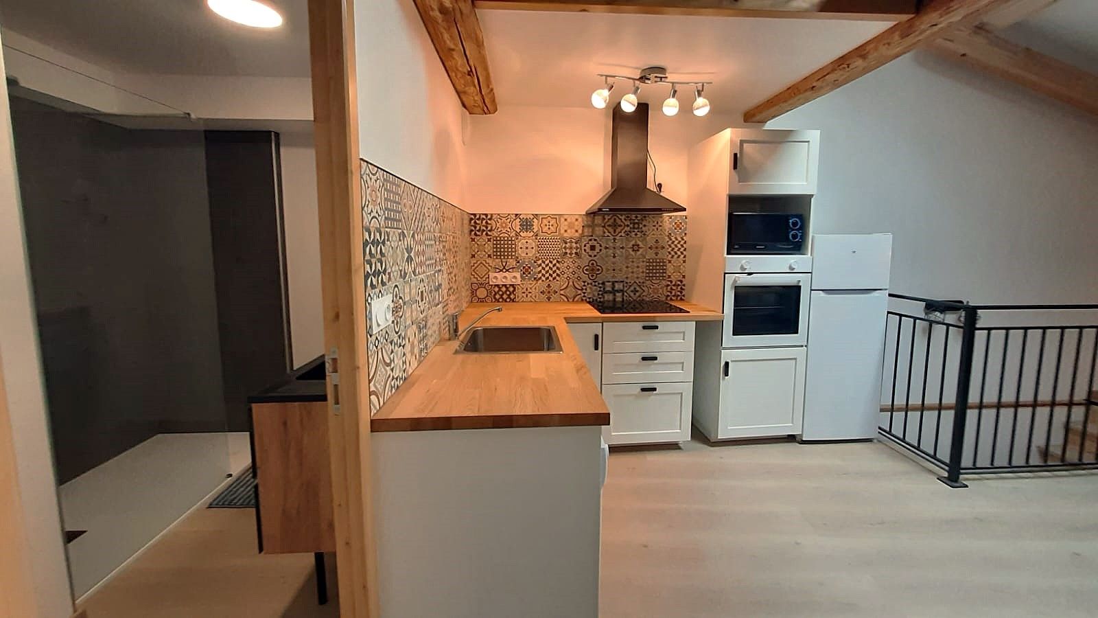Una cocina con salpicadero de diseño, horno empotrado y encimera de madera.