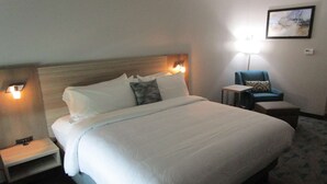 A hotel room with a large bed, bedside tables, a chair, and a lamp. - Bonham Hotel (Bonham)