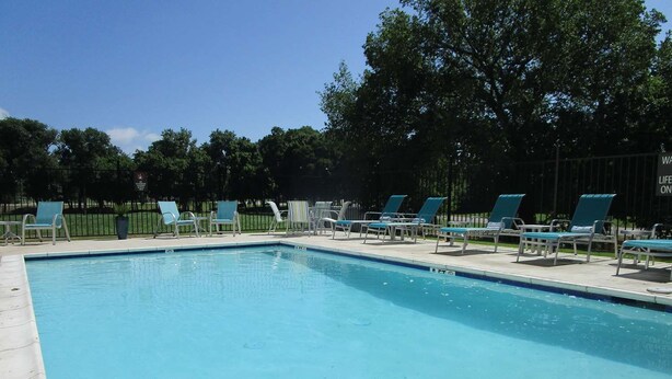 A rectangular swimming pool with a tiled edge, surrounded by lounge chairs and a metal fence. - Bonham Hotel (Bonham)