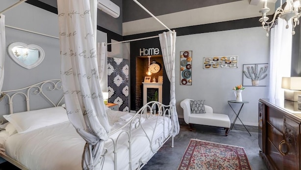 Een slaapkamer met een hemelbed, een zithoekje en een decoratieve wand.