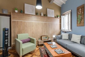 Un salon comprenant un canapé, un fauteuil, une table basse en bois et une radio.