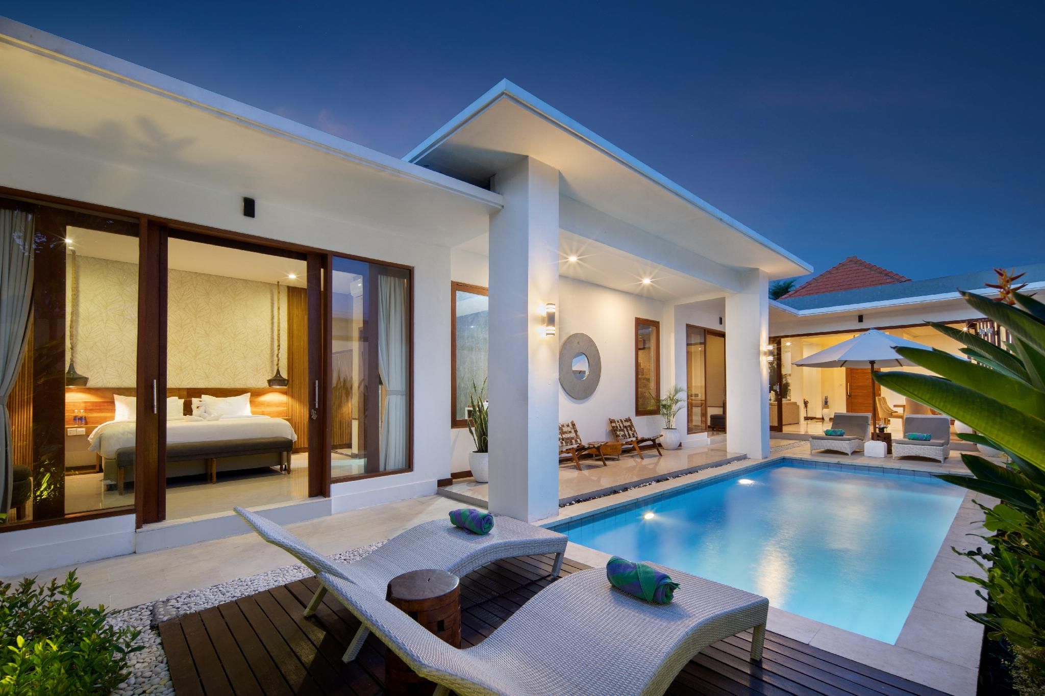 A modern hotel with a swimming pool, outdoor seating, and a well-lit interior.