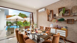 A dining area with a glass table, brown chairs, and a view of a swimming pool. - Monaco Blu Luxury Villas and Spa (Keroboken Kelod)