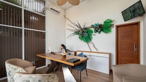 A modern room with a wooden dining table, two chairs, a decorative wall piece, a television, and a wooden door. - Monaco Blu Luxury Villas and Spa (Keroboken Kelod)