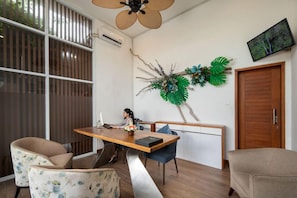 A modern room with a wooden dining table, two chairs, a decorative wall piece, a television, and a wooden door. - Monaco Blu Luxury Villas and Spa (Keroboken Kelod)