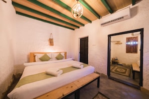 A bedroom with a wooden bed, a bench, a hanging basket, and a mirror reflecting a bathroom. - Sama Wakan (Wakan)