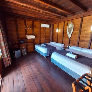 Una habitación tipo cabaña de madera con dos camas, un pequeño calentador y una lámpara colgante.