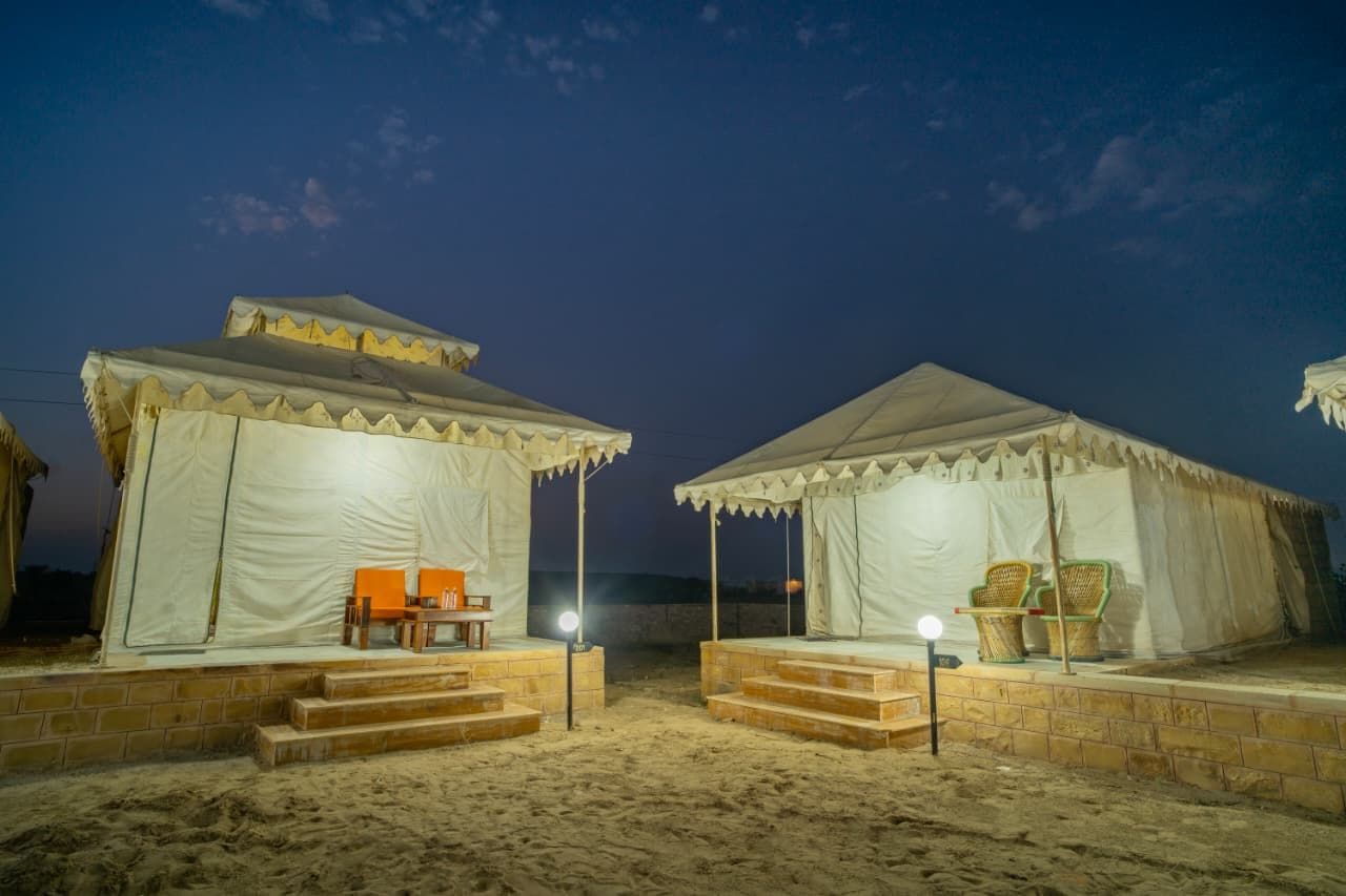 Two tents with steps leading to the entrance, each with a table and chairs.