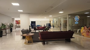 Un hall d’entrée moderne doté d’espaces de détente, d’un comptoir d’accueil et d’un mur en verre sur lequel est apposée une enseigne.