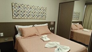 A hotel room with a bed, a nightstand, a mirror, and a wall art piece. - Park Veredas Resort (Rio Quente)