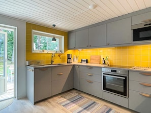 A modern kitchen with grey cabinets, a yellow backsplash, and a built-in oven. - 6 Person Holiday Home in Gunnebo (Gunnebo)