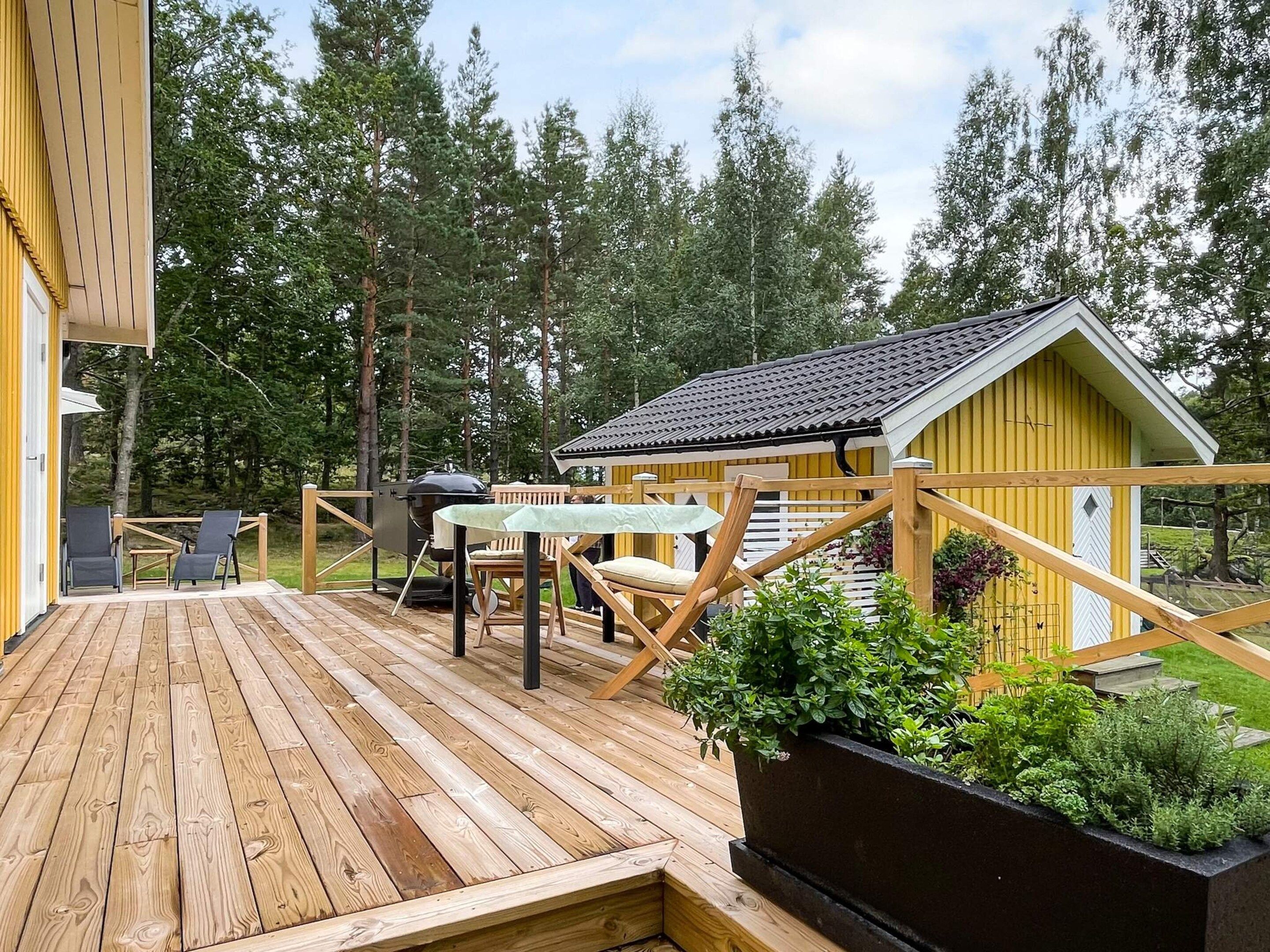 A wooden deck with outdoor furniture, a small table, and a grill area.