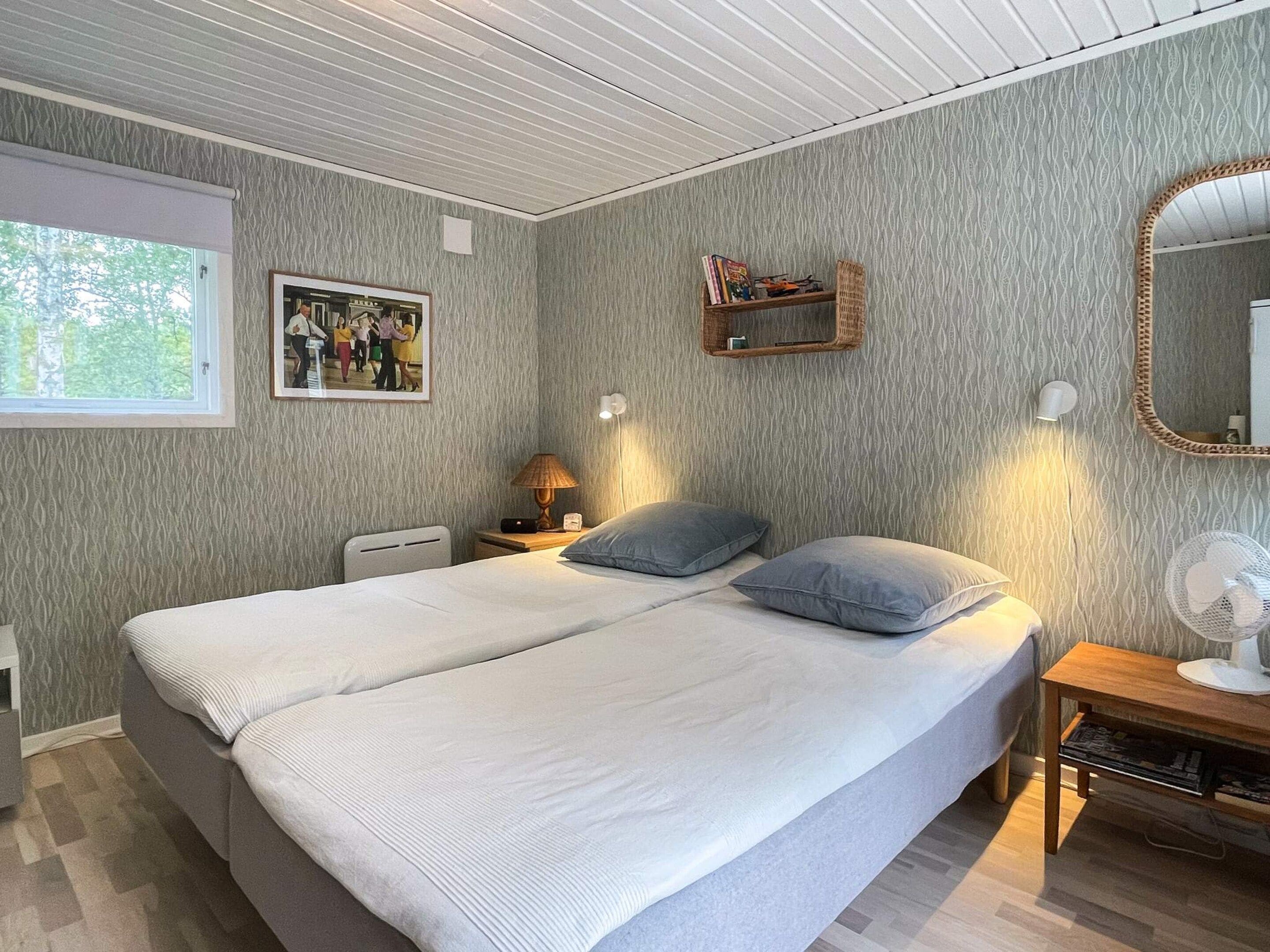 A bedroom with a bed, bedside lamps, a mirror, and a window.
