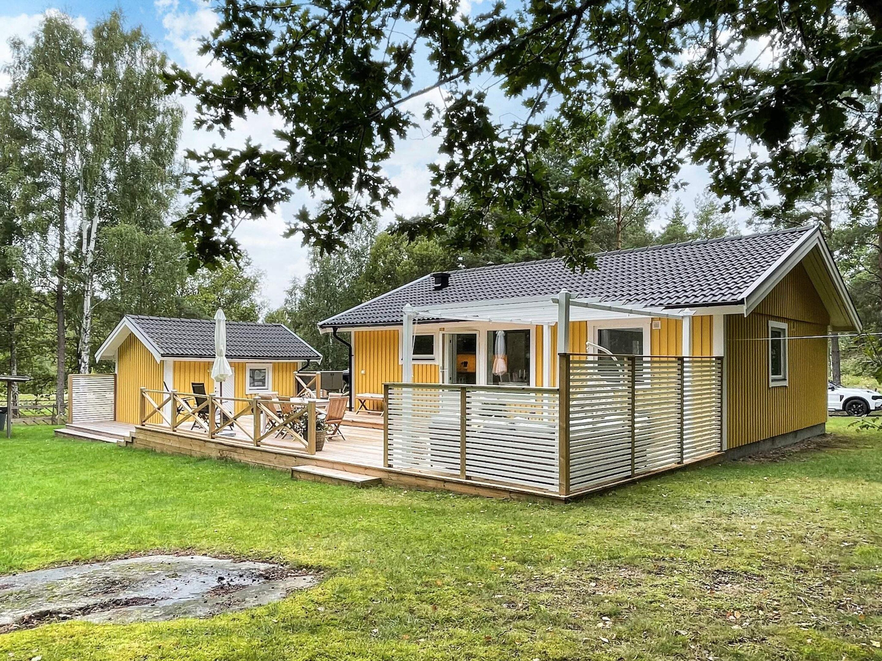 A two-story wooden cabin with a balcony, a covered patio, and a small adjacent shed.