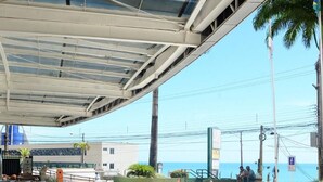 An outdoor area with a covered walkway, palm trees, and a view of the sea. - Natal Plaza Requinte Conforto E Vista Para O Mar (Natal)