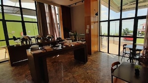 A hotel lobby with a reception desk, a coffee station, and large windows offering a view of the outside. - Natal Plaza Requinte Conforto E Vista Para O Mar (Natal)