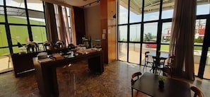 A hotel lobby with a reception desk, a coffee station, and large windows offering a view of the outside. - Natal Plaza Requinte Conforto E Vista Para O Mar (Natal)