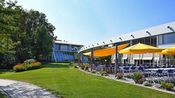 A courtyard with outdoor seating and a modern building in the background. - Genohotel (Karlsruhe)