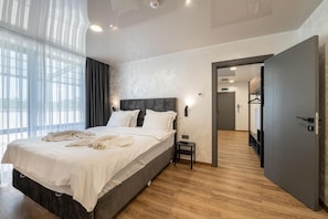 A hotel room with a large bed, a bedside table, a wardrobe, and a view through an open door. - Hotel Royal Bath (Karlovo)
