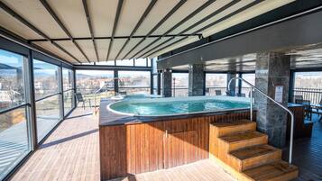 Una piscina interior moderna con una terraza de madera y vistas a la ciudad.