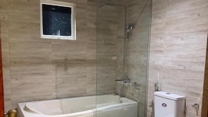 Ein Badezimmer mit einer Glasdusche, einer Badewanne und einer Toilette.