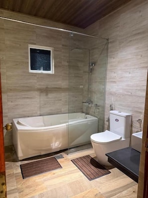 A bathroom with a glass-enclosed shower, a bathtub, and a toilet. - Don Cyril's Nature Bungalow (Galle)