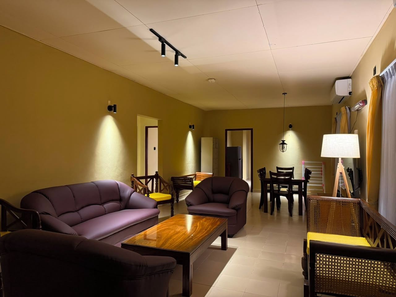 Una sala de estar con sofá, sillón, mesa de centro y un comedor con sillas y mesa.