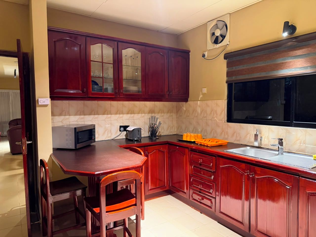 Cocina compacta con mesa de comedor, armarios de madera, microondas y un lavabo.