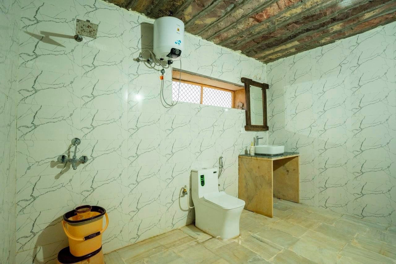 Casa de banho com sanita, lavatório e termoacumulador fixado na parede.