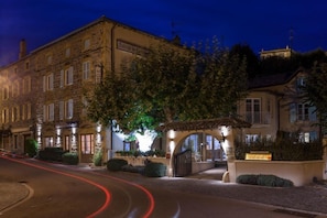 A hotel with a stone facade, a covered entrance, and a well-lit street. - Auberge De Clochemerle (Vaux-en-Beaujolais)