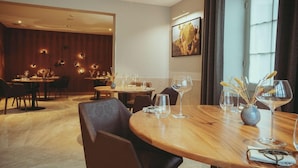 Ein Hotel-Speisesaal mit runden Tischen, Stühlen und Weingläsern.