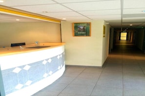 Una zona de recepción con un mostrador curvo, un cartel en la pared y un pasillo que conduce a otras habitaciones.