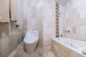 Um banheiro com vaso sanitário, banheira e parede de chuveiro revestida em azulejo.