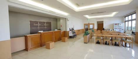 A hotel reception area with a reception desk, a clock, and a seating area with chairs.