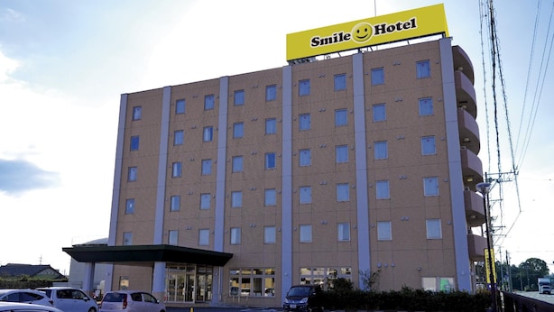 Smile Hotel -niminen rakennus, jossa on moderni muotoilu, useita kerroksia ja pysäköintialue sen edessä.