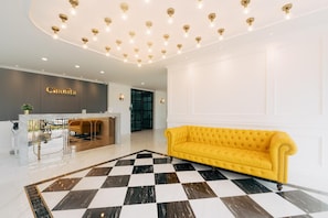 A hotel lobby with a checkered floor, a reception desk, a yellow sofa, and a ceiling with recessed lighting. - Chanita Hotel Chumphon (Chumphon)