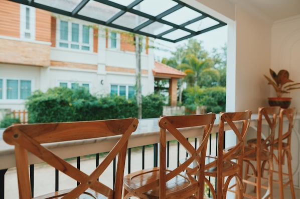 A wooden chair with a metal frame, positioned on a balcony with a view of a building and greenery. - Chanita Hotel Chumphon (Chumphon)